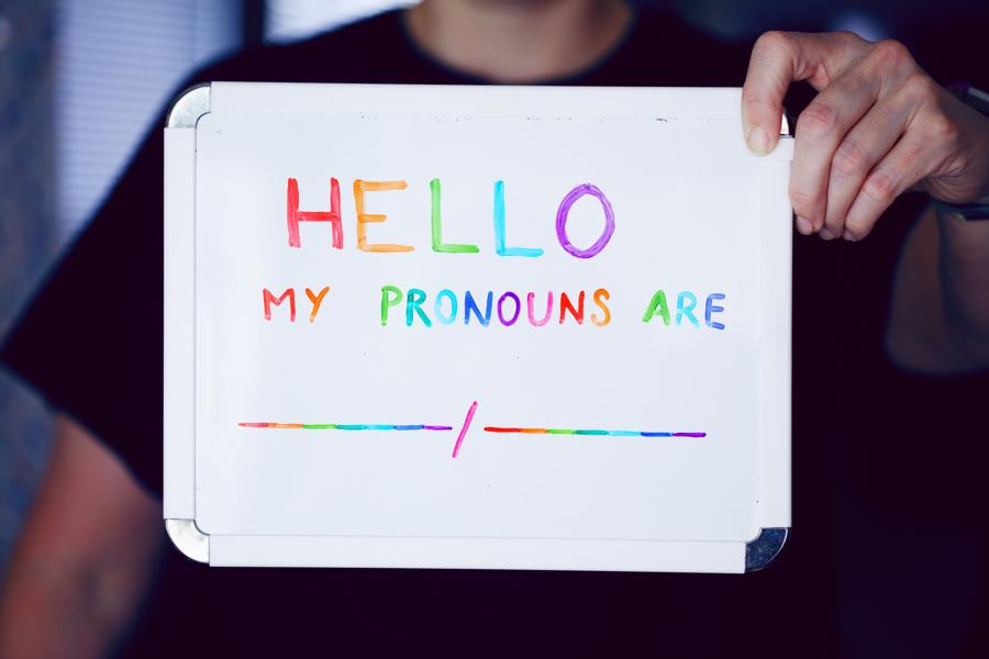 Hand-lettered rainbow sign reading Hello, my pronouns are